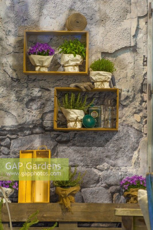 Boîtes suspendues avec herbes sur mur de pierre dans une cour italienne contemporaine. 