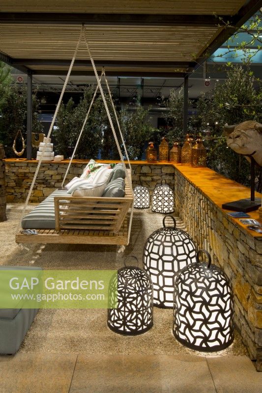 A sitting area on a gravel surface surrounded by a low stone fence with a wooden swing with pillows among many standing bright luminescent waterproof handmade decorative lamps in Luxurious African lodge.
Designer: Vetschpartner, Berger Gartenbau and Livingdreams. Giardina-Zurich, Swiss.





