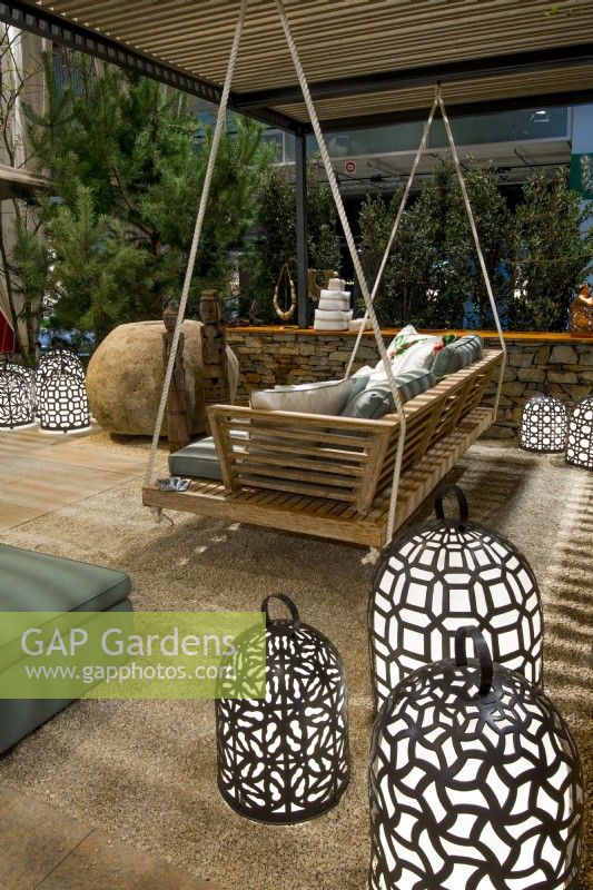 A sitting area on a gravel surface surrounded by a low stone fence with a wooden swing with pillows among many bright luminescent waterproof handmade decorative lamps in Luxurious African lodge.
Designer: Vetschpartner, Berger Gartenbau and Livingdreams. Giardina-Zurich, Swiss.






