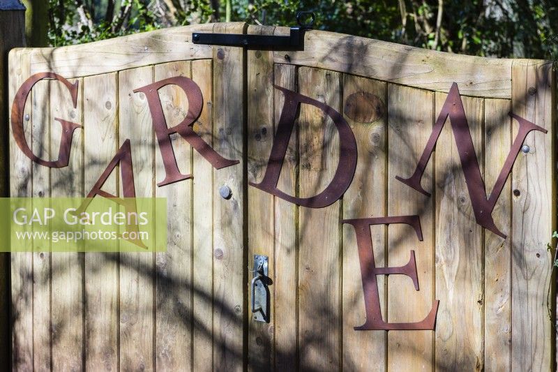 Le mot « Jardin », les lettres en acier doux rouillé attachées à la porte d'entrée en bois du jardin Veddw. 