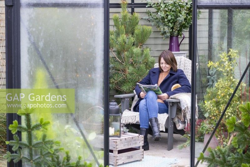 Woman reading magazine inside decorated greenhouse