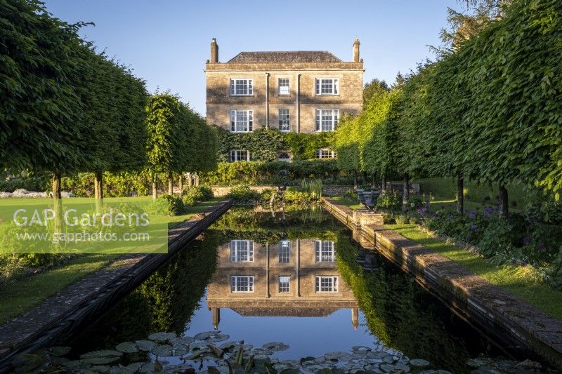 View towards Daglingworth House, Gloucestershire across the formal garden pond with a perfect reflection of the house