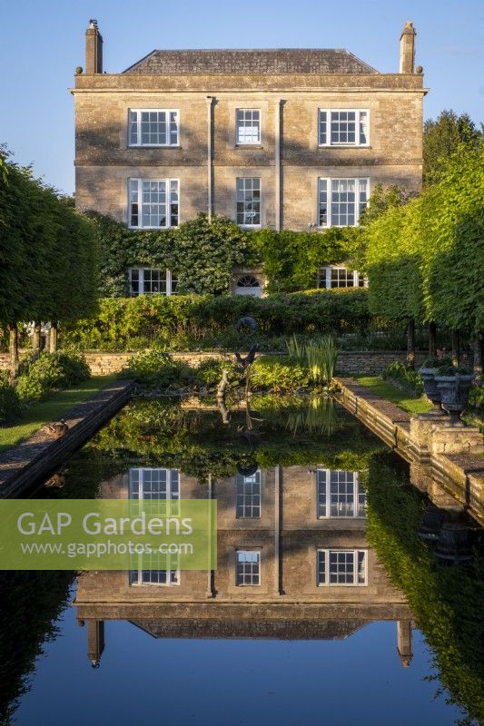 Vue vers Daglingworth House, Gloucestershire, à travers l'étang du jardin formel avec un reflet parfait de la maison 