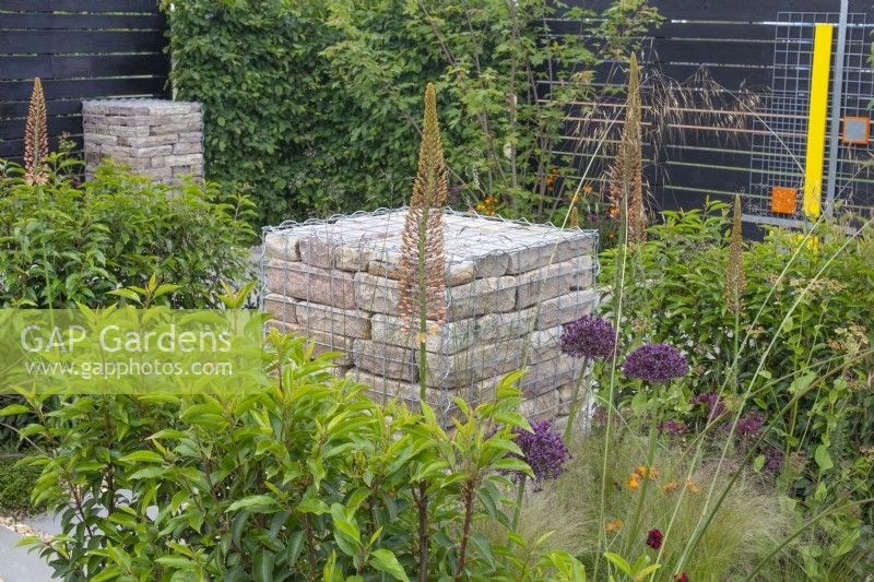 Gabions remplis de briques entourés de plantes vivaces telles que des alliums, des eremurus et des graminées dans le jardin « Slow Burn » au BBC Gardener's World Live 2015, juin 