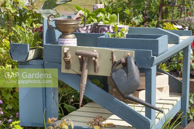 Table d'empotage bleue en bois avec outils de jardin et pots à gobelets en carton recyclé, juin 