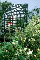 Treillis avec fond miroir reflétant la plantation dans le jardin