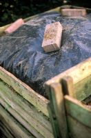 Bac à compost en bois recouvert de polyéthylène noir pour augmenter la chaleur et accélérer le compostage