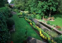 Jardin en terrasses avec parterres de fleurs, canal et marches