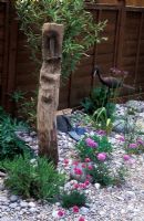 Petit jardin de style balnéaire avec galets, épi en bois, Armeria maritima et Scabiosa 'Butterfly Blue'