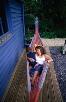 Femme se détend dans un hamac sur la terrasse en bois avec son fils