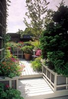Petit jardin sur le toit urbain avec une terrasse en bois et des parterres de fleurs et des pots de chrysanthème, de sauge, d'herbe, de sedum et de bétula. Banc en bois avec coussin - New York USA