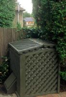 Joli bac à compost en bois peint en vert dans un coin de jardin par une clôture dans le jardin de Londres