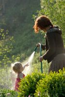 Femme et petit enfant arrosant le jardin