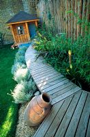 Passerelle de terrasse en bois incurvé reliant la terrasse en bois à la maisonnette