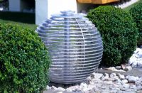 Une pièce d'eau sphérique avec des boules de topiaire Buxus coupé dans le jardin 'The Winalot Live a Lot' conçu par Chris Beardshaw au RHS Hampton Court Flower Show