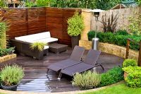 Terrasse en bois avec mobilier moderne et chauffe-terrasse dans un jardin urbain. Lavandula - Lavande en pot. Muswell Hill, Londres