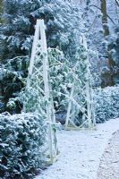 Jardin de ville formelle avec des obélisques en bois recouverts de neige, Oxford, UK.