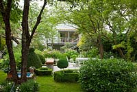 Jardin ombragé avec salon de jardin, topiaire, une haie et un petit bassin d'eau. Les plantes comprennent Buxus, Prunus laurocerasus et Prunus serrula var. tibetica - Allemagne