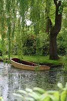 Vieux bateau à rames en bois dans l'étang ombragé par un saule pleureur - Sallowfield Cottage B