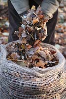 Jardinier remplissant un sac de feuilles de jute biodégradable plein de feuilles