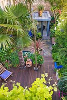 Vue sur petit jardin de ville avec terrasse en bois et bureau de jardin