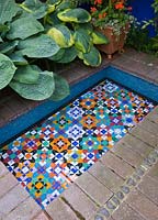 Piscine de style marocain bordée de mosaïques entourée d'Hosta dans un petit jardin de la ville - Brighton, Royaume-Uni