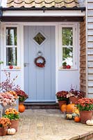 Décoration de porte d'entrée décorée pour l'automne avec des courges, des citrouilles, des chrysanthèmes