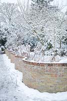 Mur de jardin en serpentine avec de la neige. Mur de manivelle froissé.