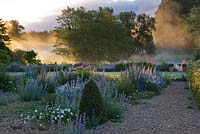 Lumière de l'aube sur le fleuve nar et le jardin de gravier devant le hall. Jardins de Narborough Hall, Norfolk