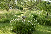 Le cadran solaire au milieu du petit verger est entouré de doubles roses blanches. Forest Lodge, Pen Selwood, Somerset, Royaume-Uni