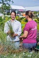 Clientèle recevant des conseils sur les herbes, d'un employé d'un centre de jardinage