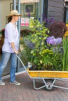 Femme poussant le chariot de plantes achetées, hors de la jardinerie