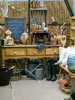 En serre, la vieille commode en pin offre un espace de travail pour les pots en terre cuite, la ficelle, les étiquettes, les gants et les listes. Bottes, arrosoirs, fourchette et trug.