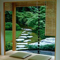 Vu de la véranda, le paysage japonais naturel idéalisé d'un ruisseau sec, une piscine peu profonde alimentée par une chaîne de pluie depuis le toit, les rochers, le chemin de pierre et le bois.