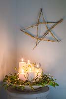 Une étoile festive faite de Prunus avec des boutures de lichen, accompagnée de bougies et de gui.