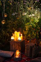 Une collection de bougies illuminant doucement un jardin la nuit.
