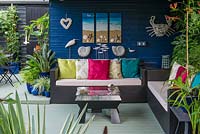Un coin salon couvert avec des décorations inspirées de la mer, un canapé et une table.