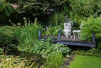 Une petite terrasse en bois surélevée et un coin salon donnant sur un étang.