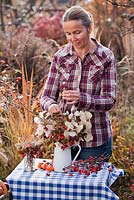 Création d'un décor floral avec des fleurs vivaces séchées en novembre: cynorhodons, honnêteté, Sedum, Aster, Persicaria
