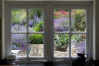 Une vue de la véranda d'une terrasse et d'un coin salon planté de vivaces et de graminées ornementales.