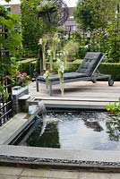 Petit étang rectangulaire avec cascade et terrasse en bois. Agapanthus orientalis Blanc en pot. Famille Fabry - Mathijs. Belgique