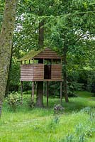 Une cabane en bois se trouve sur des échasses dans les bois.