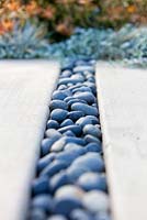 Galets décoratifs ton sur ton utilisés comme substitut de morta dans les espaces entre les dalles de pavage en béton blanc modernes. Jardin de Debora Carl, Encinitas, Californie, USA. Août.