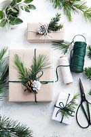 Cadeaux emballés avec du papier brun et de la ficelle avec des bobines de ficelle, décorés de verdure à partir de feuillage de sapin et d'if avec des pommes de pin à moitié trempées