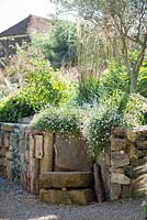 Parterre de fleurs de fin d'été avec chemin de gravier et parterre de fleurs en pierre surélevée. Conception du jardin Jo Thompson, Ticehurst, East Sussex