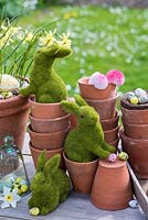 Lapins de Pâques jouant dans des pots en terre cuite avec des œufs et des fleurs