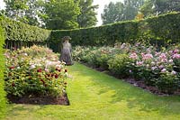 David a planté la roseraie en 2015 et a placé l'une de ses sculptures préférées de Pat, son épouse de la Dame avec les canards sur la tête sur le chemin d'herbe entre les deux parterres de fleurs.