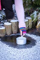 Faire fondre la glace sur un étang gelé avec une casserole d'eau chaude