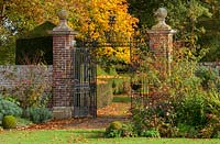 Portes de fer dans le jardin clos formel avec des couleurs automnales de parterres et d'arbres