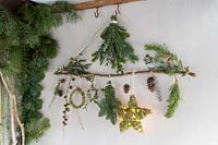 Décorations de Noël en matériau naturel - branche décorée d'étoiles, guirlande, feuillage et lumières LED dans un cadre rustique